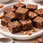 Basische Kakao Dattel Bites mit Mandeln als gesunder Snack auf einem Teller angerichtet