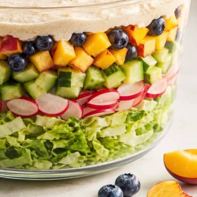 Basischer Schichtsalat mit Pfirsich, Heidelbeeren, Gurke, Radieschen und Mandeldressing Nahaufnahme