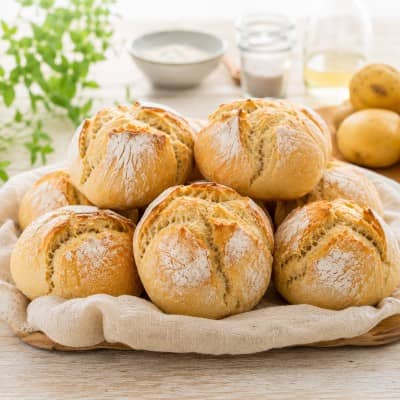 Frisch gebackene Kartoffelbrötchen mit Kartoffeln und Zutaten auf dem Tisch